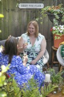 Sarah Hall and friend enjoying wine o'clock  in small suburban garden in Lichfield, Staffordshire, July