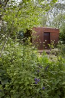 Centre for Mental Health's The Balance Garden. Designers: Jon Davies and Steve Williams. Chelsea Flower Show 2023. Reclaimed steel 'mushroom den'. Climate resilient garden with edible plants and weeds for wildlife diversity.