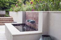 White rendered and brick raised pool with verdigris basin fountain with borders above 