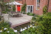 Courtyard garden with sandstone paving, garden furniture and a brick edged small water feature with bubble fountains 