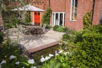 Courtyard garden with sandstone paving, garden furniture and a brick edged small water feature with bubble fountains 