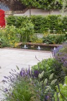 Courtyard garden featuring a brick lined pool with bubble fountains with yellow and white planting scheme.