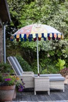 Loungers below a decorative umbrella on a terrace in July