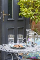 Metal table with a jug and glasses of water with cookies
