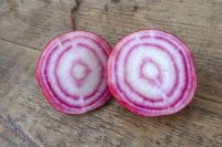 Beta vulgaris 'Chioggia' beetroot freshly harvested from the allotment on a wooden work top. Sliced to show the red and white concentric rings. 