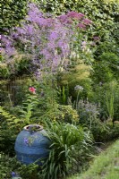 Large blue oil jar surrounded by lush planting in August
