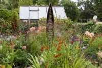 Seed Pod by Ted Edley surrounded by orange and purple planting including heleniums, dahlias and salvias in September