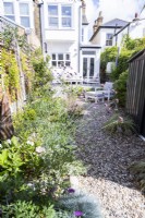 Gravel path along border past shed towards raised patio and house from end of garden