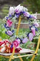 Wreath made of tulips, muscari, cow parsley and myosotis displayed on seat.