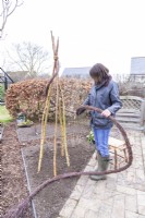 Woman wrapping birch garland in a spiral around the sticks from the top
