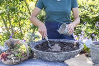 Woman mixing grit in with the compost in the shallow container