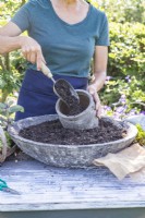 Woman filling pot with compost