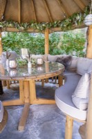 Seating and wooden table with glass top on animal skin rug inside wooden gazebo