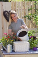 Woman filling wicker container with a mixture of compost and good soil to create good growing condition for plants.