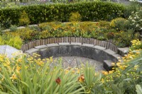 Journey to the Sun, the sunken barbeque area amongst a profusion of yellow and orange planting. Harbour Lights, Devon NGS garden. July. 