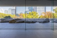 View from inside building through glass walls to landscaped area of rocks intended to represent the Canadian Shield. View to trees with autumnal colour and  to surrounding buildings.
