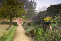 Path beside the hot border in the walled garden at Parham House in September