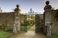 A view into the walled garden through ornamental gates flanked by stone lions at Parham House in September