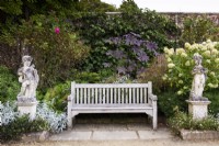 Wooden bench flanked by stone cherubs in the walled garden at Parham House in September