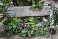 Pinecones, Ivy Hedera and Yew sprigs around the bottom of a wooden crate