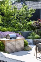 Wooden unit with barbecue on terrace of modern garden