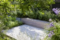 Raised paved area with built-in seating surrounded by soft planting