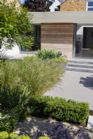 Cotswold stone path next to paved patio area of modern garden