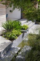 Raised metal bed with water feature in modern garden