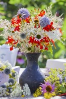Summer bouquet with Echinops, Crocosmia, Persicaria polymorpha, Echinacea purpurea and Ammi majus in black vase.