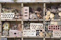 An insect bug hotel made from reclaimed reused materials and wood off cuts and pine cones for insects habitats