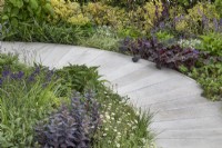 Curved path intersecting beds of perennials in 'Here We Go Round The Mulberry Bush' garden at BBC Gardener's World Live 2019, June