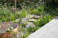 Composite decking board next to a stream and metal copper container water feature