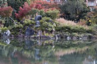 Border of shrubs, grasses and rocks reflected in the water of the Ingestu-chi pond. 