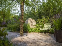 Seating area with green Fernob chair next to Betula nigra and stone cairns at Horatio's Garden, Chelsea Flower Show 2023. Designer: Charlotte Harris and Hugo Bugg, Gold medal winner, Best Show Garden