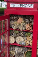 An insect hotel made by children from a model red telephone box