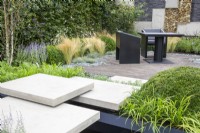 Floating concrete stone stepping stones steps leading to a brick paved patio area with black table and chairs 