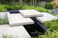Floating concrete stone stepping stones steps over a black rill
