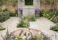 Stone paved patio with a corten steel fire bowl, dining area with purple bar stools, mixed perennial planting in purple and white colours