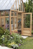 Wooden glasshouse with perennial bed, June