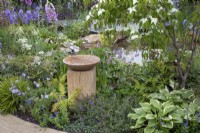 Wooden bird bath set amongst mixed perennial planting in the 'RHS Garden for Wildlife Wild Woven' - RHS Chatsworth Flower Show 2019, June
