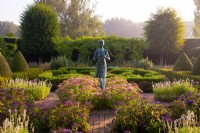 The Lamp of Wisdom statue surrounded by Sedum 'Autumn Joy', Heliotropium arborscens and Box and Yew topiary in the formal garden at Waterperry Gardens
