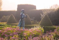 The Lamp of Wisdom statue surrounded by Sedum 'Autumn Joy' , Heliotropium arborescens, Yew and Box topiary in the formal garden at Waterperry Gardens