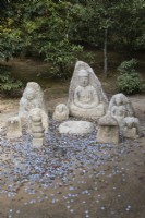 Group of stone Buddhas with coins on ground as offerings. 
