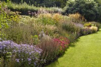 Large sweeping ornamental grass and flowering perennial border in the private family garden at Cambo House, Fife, Scotland.