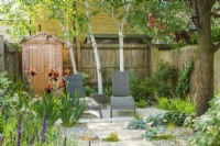 Small contemporary town garden in summer with stepping stones. Wide variety of foliage and floweering plants including birch trees, Iris 'Natchez Trace'and Salvia nemorosa 'Caradonna'. June