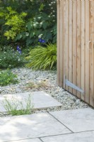 Detail of limestone paving design and planting in front of timber garden store in contemporary town garden. June