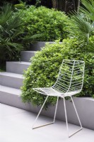 White metal garden chair on paved area next to steps