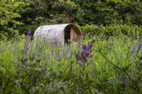 Wooden sauna set into a perennial wildflower meadow.