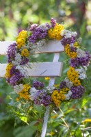 Wreath made of Tansy, Verbena bonariensis, yarrow, and Fennel foliage hanging from a chair.