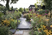 Late summer garden with garden office and Rudbeckia 'Goldsturm', Cosmos bipinnatus 'Dazzler' and Echinops

